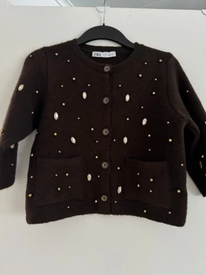 Brun trekvarts kofta från Zara - Så fin trekvartsärmad brun kofta från Zara med rund halsringning och pärlor och paljetter över hela plagget. Storlek S men passar fint för XS och även M. Koftan har knäppning framtill med fem knappar och två praktiska fickor. Den är knappt använd 💕💕