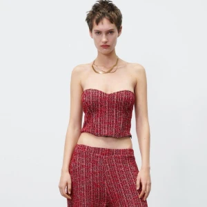 Röd bandeau topp i tweed - Trendig röd bandeau topp i tweed-look med inslag av vitt och svart. Toppen är axelbandslös och croppad, perfekt för en cool och modern stil. Passar dig som vill sticka ut med en unik topp i snygg struktur.