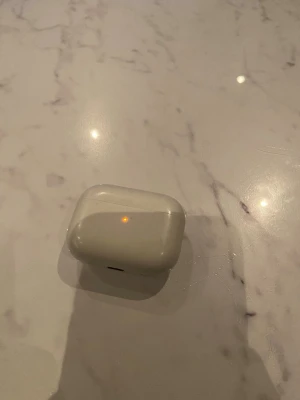 Apple AirPods Pro  - Säljer ett par Apple AirPods Pro med vitt laddningsetui. Trådlösa in-ear-hörlurar med stilren och kompakt design. Perfekta för musik, poddar och samtal. Laddningsetuiet är i blankt plastmaterial och hörlurarna är vita.