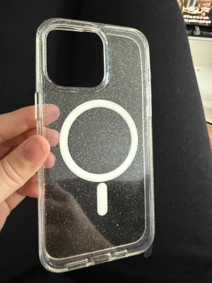 MagSafe Glitter Skal iPhone 15 Pro Max - Helt ny och oöppnad. Råkade köpa fel modell så den första bilden är det jag använder just ny. Super snyggt genomskinligt mobilskal med glittereffekt från Tech Protect, designat för iPhone 15 Pro Max. Skalets hybridmaterial ger bra skydd och MagSafe-kompatibilitet gör det enkelt att använda trådlös laddning och MagSafe-tillbehör. Perfekt för dig som vill ha både stil och funktion.