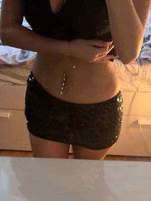 Svart paljettkortkjol - Säljer en svart kortkjol täckt med glittriga paljetter. Kjolen har en tight passform och är perfekt för dig som vill sticka ut. Ingen synlig dragkedja eller knappar, bara ren partyvibe.