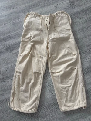 Vida beige linnebyxor Bershka - Säljer ett par vida linnebyxor i beige med drag i midjan och fickor på sidorna. Byxorna har avslappnad passform och resår bak i midjan för extra komfort. Perfekta för en chill och stilren look. Från Bershka