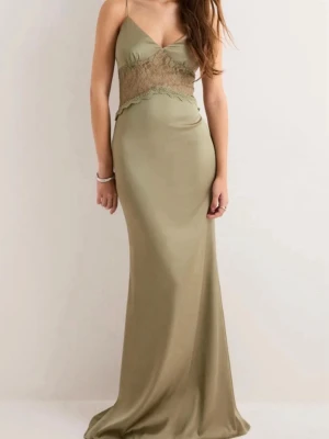 Olivgrön långklänning med spets - Snygg olivgrön långklänning med tunna axelband och v-ringning. Klänningen har spetsdetaljer i midjan och öppen rygg med snörning. Helt oanvänd med prislapp kvar!