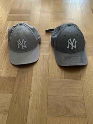 Grå New York Yankees keps - Säljer en stilren grå New York Yankees keps från New Era med klassisk böjd skärm och broderad vit NY-logga framtill. Justerbar rem baktill för perfekt passform. Kepsen är tillverkad i ett mjukt och slitstarkt material som passar till alla tillfällen. 115 kr styck, båda för 200kr