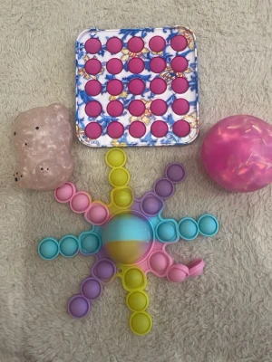 Fidgettoys - En pop it med plast bakgrund, en rosa frysta stressboll, en bläckfisk pop it och en björn stressboll