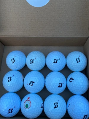 Bridgestone mix 24-pack - Säljer 24st golfbollar i märket Bridgestone . levererade i en kartong. Bollarna har klassiskt dimple-mönster och märkning med siffror och logotyp. Perfekt för golfentusiasten som vill ha kvalitetsbollar till nästa runda.Fint skick vi är ärliga dm vi frågor😊👍🏻