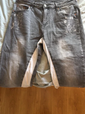 Gråa raka jeans med vit kil - Unika gråa jeans med raka ben och vit kil på insidan. Jeansen har fem fickor, slitna detaljer och ljusa partier framtill och baktill. Materialet är klassisk denim i bomull. Perfekt för dig som vill sticka ut med en cool och annorlunda look.