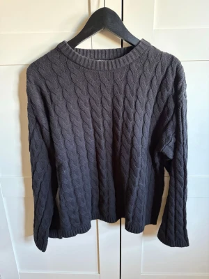 Svart kabelstickad tröja Gina Tricot - Säljer en svart kabelstickad tröja från Gina Tricot. Tröjan har rund halsringning, långa ärmar och ribbade muddar. Perfekt för dig som gillar klassisk och enkel stil. Materialet är mjukt och bekvämt, och passar bra till jeans eller kjol.