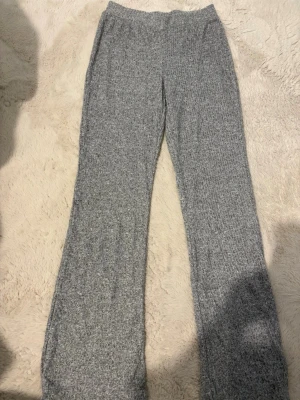 Grå ribbade loungewear-byxor 157 - Mysiga grå loungewear-byxor från lager 157 i ribbat material. Byxorna har en mjuk resår i midjan och raka ben, perfekta för chill dagar hemma. Materialet känns stretchigt och bekvämt, och färgen är lätt att matcha med andra plagg.