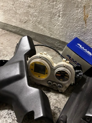 Aerox delar ( buda ) - Säljer ett svart mopedpanelkit från Yamaha med tillhörande instrumentpanel, hastighetsmätare och bränslemätare. Panelen är tillverkad i plast och har en modern design. Inkluderar även backspegel och RMS-låda. Perfekt för dig som vill uppgradera eller reparera din moped.