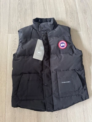 Canada Goose Väst - Canada Goose Väst                                                                     Storlek: M                                                                                       Helt ny och kommer med original lappar.                               Kan skickas med PostNord eller hämtas i Uppsala.