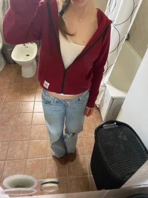 Vinröd hoodie från Andy by Frank Dandy - Vinröd hoodie med dragkedja från Andy by Frank Dandy. Tröjan har huva, svarta detaljer och en liten vit logolapp nertill. Tillverkad i mjukt material som känns skönt mot huden❤️.