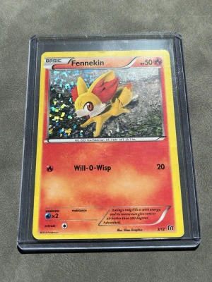 Pokémonkort Fennekin holo 3/12 2016 - Säljer ett Pokémonkort med Fennekin, holo-variant från 2016. Kortet har en röd och gul design med glittrande effekt och är skyddat i plastficka. Perfekt för samlare eller Pokémonfans som vill utöka sin samling. 2016 Mcdonalds kort med värde upp mot 350kr
