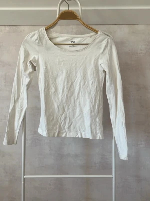 Vit långärmad topp från 157 - En enkel och stilren vit långärmad topp från 157. Modellen har rund halsringning och är figurnära i passformen. Tillverkad i mjuk bomull som känns skön mot huden. Perfekt att matcha med jeans eller kjol för en clean look.