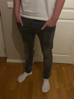 Grå slim fit jeans - Säljer ett par grå slim fit jeans med lätt slitning och klassisk femficksdesign. Jeansen har smal passform och normal midja, perfekta för en trendig och avslappnad look. Materialet är stretchigt för extra komfort. Storlek 32-33!