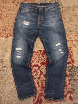 Nudie Jeans Steady Eddie II - Säljer ett par helt nya jeans från Nudie med coola slitningar samt wash. De har även ett coolt tryck mönster som syns på bilderna! De är i storlek W32 L32 och måtten är följande:                      Midja- ca 87 cm                                                       Innerbenslängd - 82cm                                           Fotöppning - 19cm                                                        Skriv vid minsta fundering pris kan diskuteras!