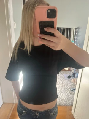 Svart  t-shirt - Säljer en svart  t-shirt med längre ärmar. Perfekt för dig som gillar en enkel och stilren look. T-shirten har en tight passform och passar bra till jeans eller shorts. Den har knytning i ryggen 