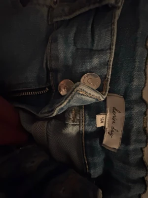 ljusblå jeans från denim day - Snygga blå jeans från Denim Day med klassisk femficksdesign och dragkedja framtill. Jeansen har en ljus tvätt och silverfärgade knappar. Perfekta för en avslappnad och trendig look. 