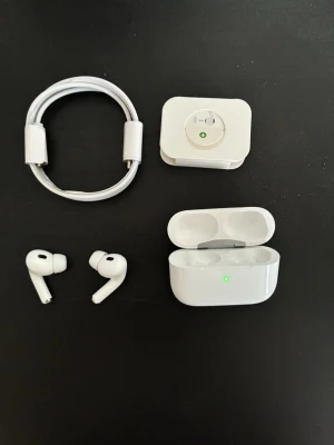 Apple AirPods Pro med laddningsetui - Säljer ett par vita Apple AirPods Pro med trådlöst laddningsetui, USB-C laddkabel och adapter. Hörlurarna har en stilren design i blank plast och silikonproppar för bra passform. Perfekt för dig som vill ha grymt ljud och brusreducering.