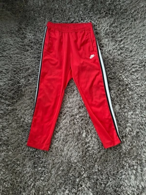 Röda Nike dress - En röd Nike dress, med Nike märket på bröstet o på låret. Byxorna har en skön pass form och funkar till träning men även chill hemma