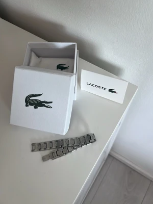 Lacoste Armband  - Säljer denna feta Lacoste armband i ett mycket bra skick. Den är knappt använd och kommer i box, dustbag och kort. Kontakta vid  frågor eller funderingar!
