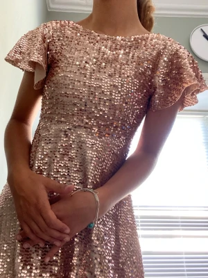 Ljusrosa/guld/rosé/champagne paljettklänning - ❣️Gammal bildtagning❣️Superfin Zara klänning täckt av glittriga paljetter. Klänningen har korta, volangiga ärmar och rund halsringning. Perfekt för dig som vill sticka ut med en glammig look. Passar en Xs. Materialet känns mjukt och följsamt.