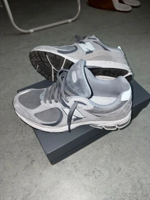 Grå New Balance 2002R sneakers - Snygga grå New Balance 2002R sneakers med mesh och mockadetaljer. Skorna har en chunky sula och klassisk N-logga på sidan. Perfekta för dig som gillar stilrena och bekväma sneakers med sportig vibe.