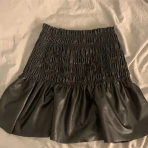 Svart kortkjol i skinnimitation Gina Tricot - Oanvänd. Strl Xs men funkar som S. Från Gina Tricot i skinnimitation. Perfekt att styla med en enkel topp