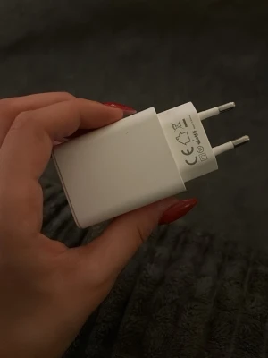Vit USB-laddare med USB-C och USB-A - Praktisk vit väggladdare med både USB-C och USB-A port. Perfekt för att ladda mobilen eller andra enheter snabbt och smidigt. Kompakt design som är enkel att ta med sig. Passar de flesta mobiler och tillbehör.