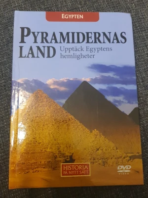 Pyramidernas land bok + DVD - En illustrerad bok med hård pärm om Egyptens pyramider och deras hemligheter. Omslaget har foton på pyramider mot blå himmel och boken ingår i serien 'Historia på nytt sätt'. Inkluderar även en DVD-video för extra upplevelse.