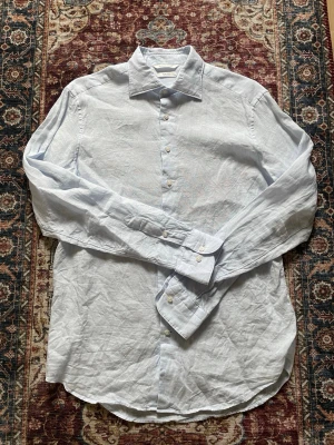 Linneskjorta från suitsupply - Säljer en ljusblå linneskjorta från suitsupply. Skjortan är i 100% linne från Albini, Italien. Använd endast en gång och säljer nu för att jag hellre vill ha pengarna. Jag är 189cm lång och storleken på skjortan är M. Skjortan kan uppfattas som skrynklig på bilderna, men går absolut att fixa genom att stryka den👍🏼