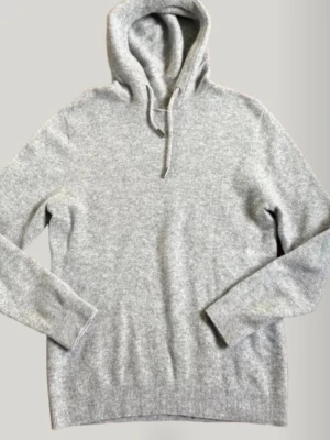 Ljusgrå cashmere blandad merinoull hoodie  - En stilren ljusgrå hoodie med huva och dragsko. Tillverkad i ett mjukt, stickat material som känns skönt mot huden. Hoodien har långa ärmar och ribbade muddar vid ärmslut och nederkant. Perfekt för en avslappnad look.