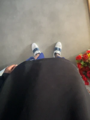 Vita Valentino sneakers med blå detalj - Snygga vita sneakers från Valentino med breda mörkblå band över vristen. Klassisk låg modell med rund tå och vita snören. Sulan är vit och har rutmönster undertill. Perfekta för dig som gillar stilrena men ändå unika skor.