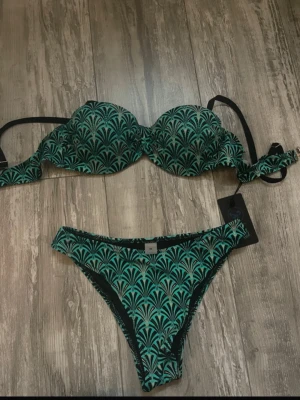 Grön och svart mönstrad bikini - Snygg bikini som jag köpte i Thailand. Överdelen har push up. Storleken är 40 men är som xs/s💓Säljer likadan i lila! 
