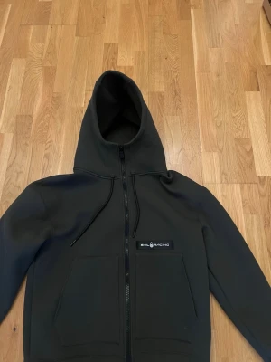 hoodie från Sail Racing - hoodie med dragkedja från Sail Racing., två stora fickor framtill och en diskret logotyp på bröstet. Perfekt för en avslappnad och sportig stil. Helt ny aldrig använd 