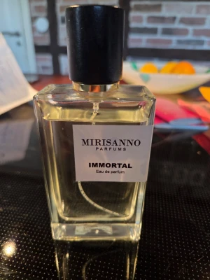 Mirisanno Immortal Eau de Parfum - Fräsch parfym från Mirisanno med namnet Immortal. Flaskan är rektangulär i genomskinligt glas med svart kork och guldiga detaljer. Passar dig som gillar stilrena och moderna dofter.