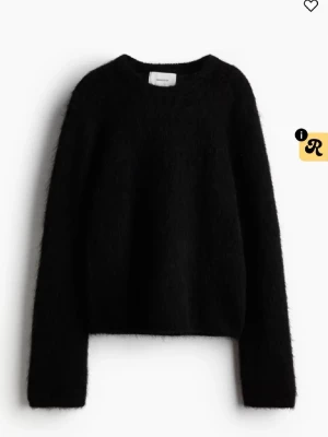 Svart fluffig mohair tröja - En svart stickad tröja med rund hals och långa ärmar. Tröjan har en fluffig och mjuk struktur som ger en cool och avslappnad look. Perfekt för att hålla sig varm och snygg under kyliga dagar. Är i mohair, så den håller dig varm 🥰 funkar till sommarkvällar också