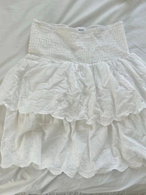 Vit volangkjol med broderad spets - Söt vit kjol från med broderad spets med blommönster och scallop-kant. 