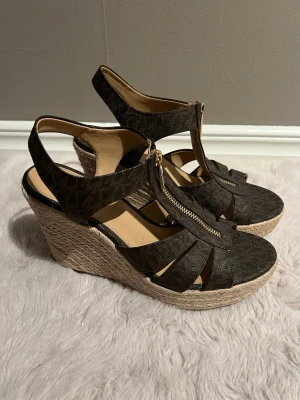 Bruna kilklackade sandaler Michael Kors - Snygga bruna sandaler från Michael Kors med kilklack🌟Inte trasiga och de är i bra skick, dock har dom använts flitigt 