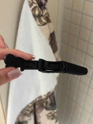 Svart hårklämma i plast - En stilren svart hårklämma i matt plast med enkel och smidig design. Perfekt för att hålla håret på plats när du stylar eller fixar frisyren. Klämman har en klassisk form och passar till de flesta hårtyper.