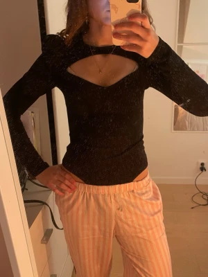 Svart body med cut out och puffärm - Snygg svart body från H&M med långa puffärmar och trendig cut out-detalj vid bröstet. Tight passform och rund halsringning. Perfekt att styla till både jeans och kjol. Materialet känns mjukt och stretchigt, vilket gör den bekväm att bära hela dagen. Aldrig använt!