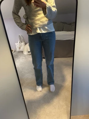 Blå raka jeans i klassisk modell - Säljer ett par blå jeans med rak passform som är low waisted. Jeansen har klassisk femficksdesign och är tillverkade i ett mjukt denimtyg. Perfekta för en avslappnad och stilren look.