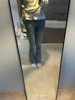 Blå bootcut jeans från true religion - Säljer ett par blå bootcut jeans med snygga fickdetaljer bak. Jeansen har en klassisk femficksmodell och är tillverkade i stretchigt denimtyg för skön passform. Perfekta till en avslappnad stil och passar till det mesta i garderoben.