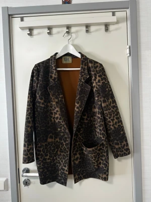 Free For Humanity brun kavaj - En leopardmönstrad kavaj med en knapp framtill och två fickor. Kavajen har en krage och slag.