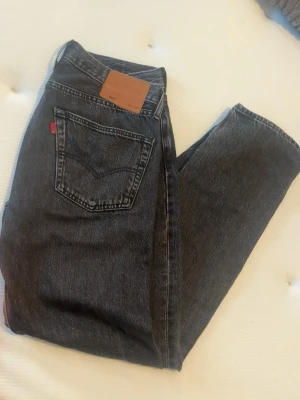 Levi's svarta raka jeans - Säljer ett par klassiska svarta Levi's jeans med rak passform och hög midja. Jeansen har fem fickor, en liten röd Levi's-tag bak och är gjorda i kraftig bomullsdenim. Perfekta till en avslappnad streetstyle-look.