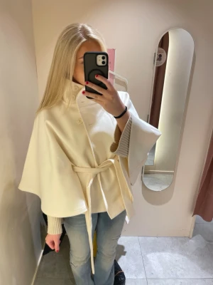 Beige cape-kappa med knytband - Säljer en vit kappa från Gina!