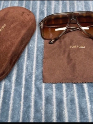 Bruna solglasögon från Tom Ford - Snygga solglasögon från Tom Ford med bruna glas. Kommer med originalfodral och putsduk i brunt. Perfekt accessoar för sommaren.