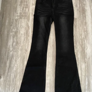 Svarta bootcut jeans med fickor - Säljer ett par svarta bootcut jeans med klassiska fickor och lätt utsvängda ben. Jeansen har en snygg tvättad look och är perfekta för dig som gillar en retrostil. Materialet känns mjukt och stretchigt för extra komfort. Aldrig använda!🥰