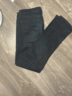 Mörkblå jeans från Nudie Jeans - Snygga mörkblå jeans från Nudie Jeans med klassisk femficksdesign och raka ben. Jeansen har en diskret logga på bakfickan och är tillverkade i ett mjukt denimtyg som sitter skönt. Perfekta för dig som gillar stilrena och tidlösa jeans.