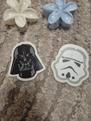 Star Wars klistermärken Darth Vader - Två klistermärken med Star Wars-tema, en med Darth Vader i svart och grått och en med en Stormtrooper i vitt och svart. Båda är formade efter karaktärernas huvuden och har tydliga detaljer. Perfekt för att dekorera laptop, mobil eller anteckningsbok.